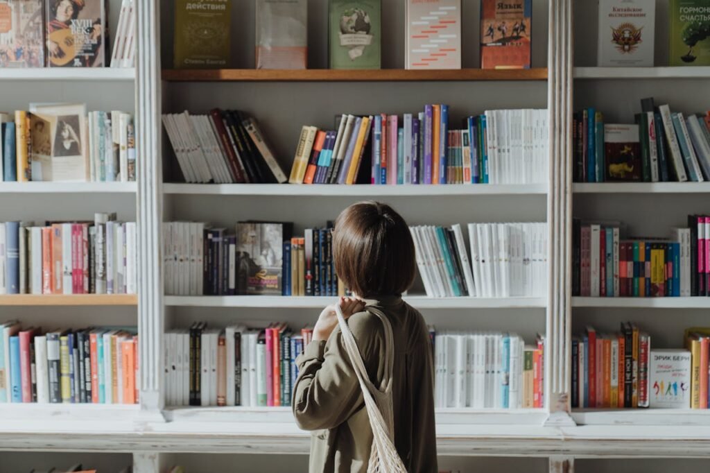 A woman browsing a bookshelf in a well-lit bookstore, exploring various titles.